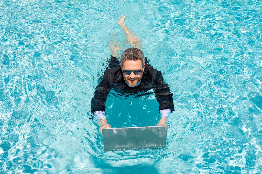 Mann arbeitet mit Laptop im Pool — Community online, wann es passt
